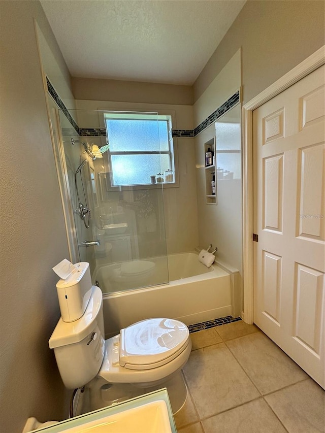 bathroom featuring toilet, a textured ceiling, tile floors, and tiled shower / bath