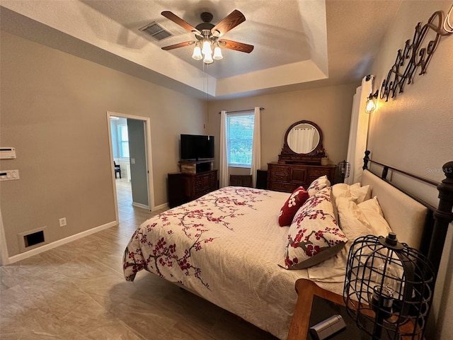 tiled bedroom featuring a raised ceiling and ceiling fan