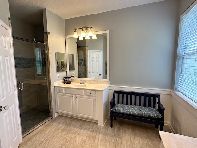 bathroom featuring vanity, a shower with shower door, and a wealth of natural light