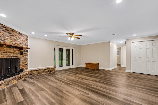 unfurnished living room featuring crown molding, ceiling fan, dark hardwood / wood-style flooring, and a brick fireplace