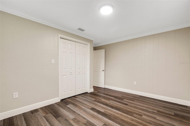 unfurnished bedroom featuring crown molding, a closet, and dark wood-type flooring