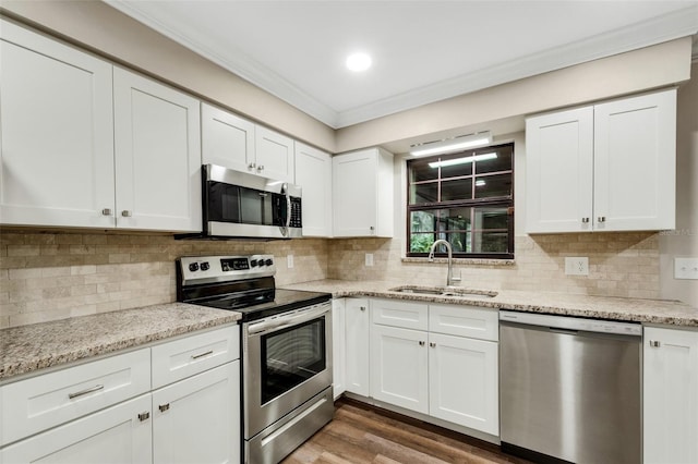 kitchen featuring wood-type flooring, white cabinetry, backsplash, and stainless steel appliances