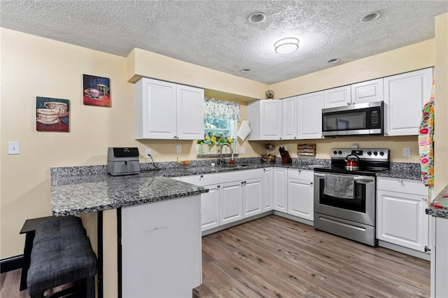 3016 Reiter Dr, Auburndale, FL 33823 - kitchen with appliances with stainless steel finishes, kitchen peninsula, white cabinetry, and light hardwood / wood-style flooring