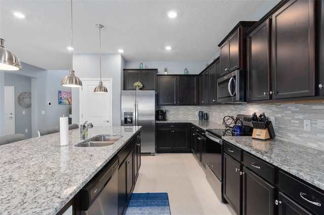 kitchen with dark brown cabinets, sink, pendant lighting, appliances with stainless steel finishes, and tasteful backsplash