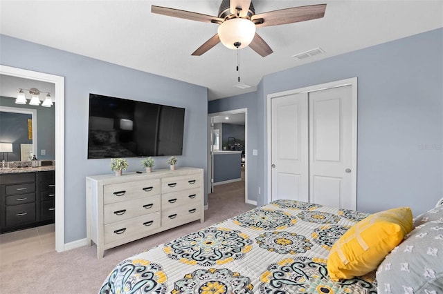 bedroom featuring a closet, ensuite bathroom, light colored carpet, and ceiling fan