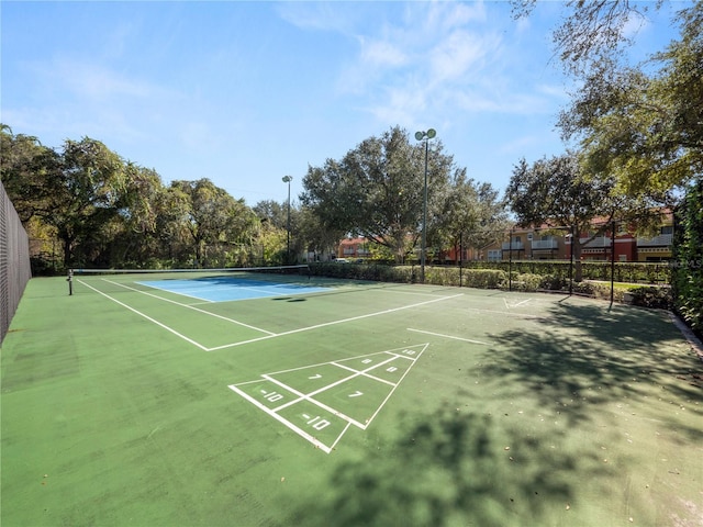 surrounding community featuring a tennis court, shuffleboard, and fence