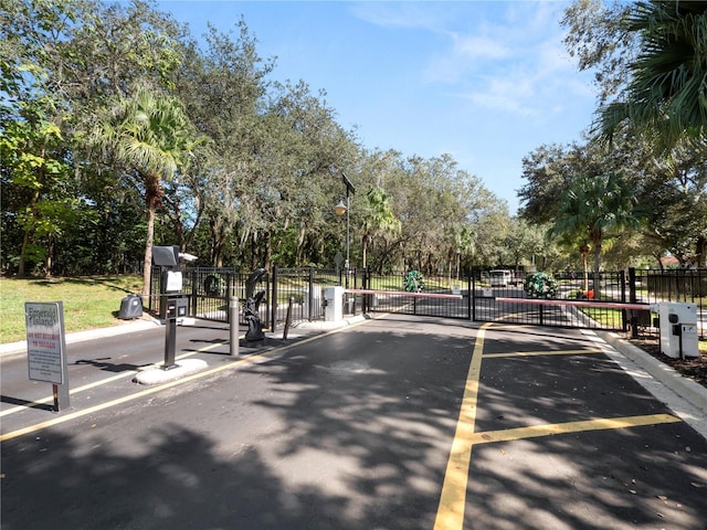 view of street featuring street lighting, a gate, a gated entry, and curbs