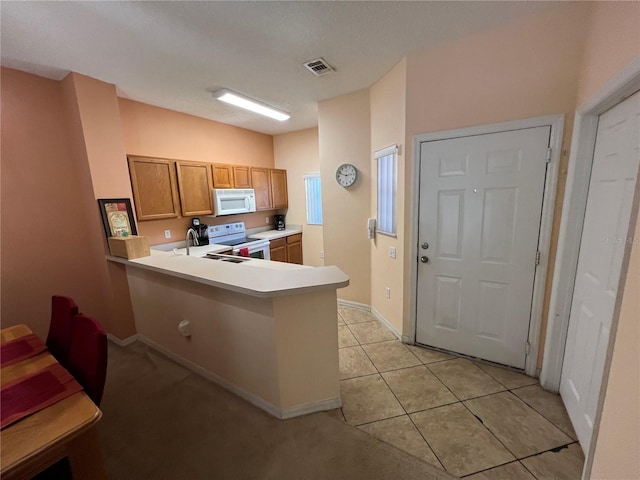 kitchen featuring kitchen peninsula, sink, light tile patterned flooring, and white appliances