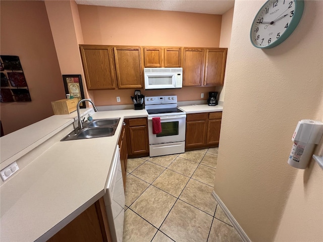 kitchen with white appliances, brown cabinets, a sink, and light tile patterned flooring