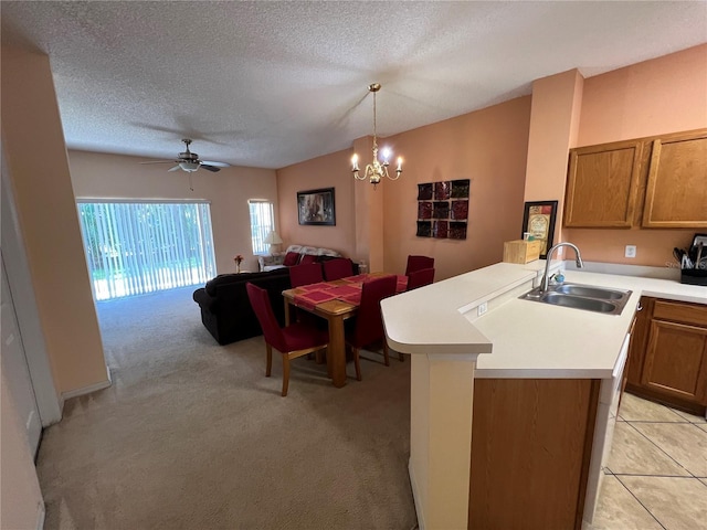 kitchen with brown cabinetry, open floor plan, a peninsula, light countertops, and a sink