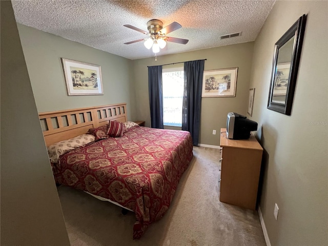 bedroom featuring light colored carpet, visible vents, a ceiling fan, a textured ceiling, and baseboards