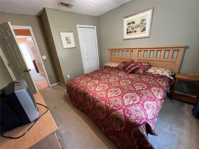 carpeted bedroom with a textured ceiling, a closet, visible vents, and baseboards