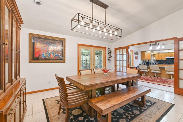 tiled dining space with vaulted ceiling, a textured ceiling, and french doors