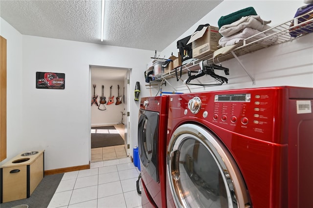 laundry area featuring washing machine and dryer, light tile patterned floors, and a textured ceiling