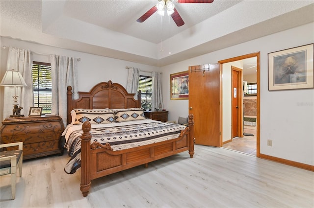 bedroom featuring ceiling fan, light hardwood / wood-style floors, connected bathroom, and multiple windows