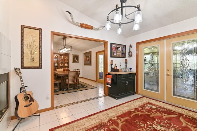 tiled entryway featuring a chandelier, french doors, a textured ceiling, and vaulted ceiling