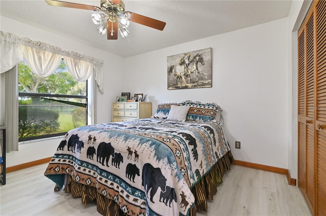 bedroom featuring a textured ceiling, light hardwood / wood-style floors, a closet, and ceiling fan