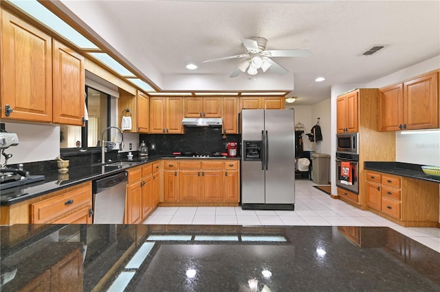 kitchen with ceiling fan, sink, dark stone countertops, light tile patterned floors, and appliances with stainless steel finishes