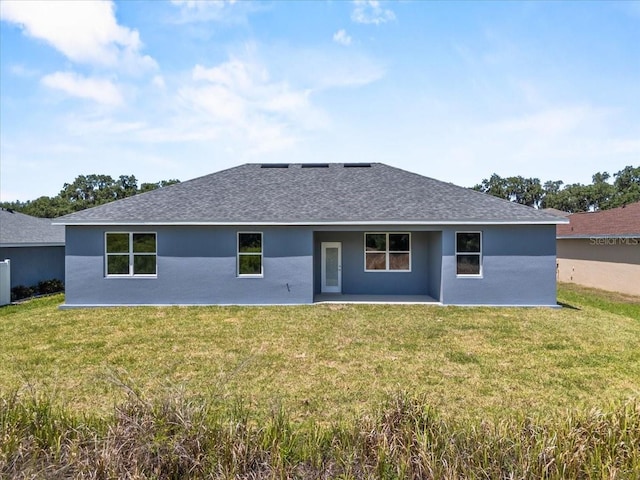 back of property featuring a lawn, a patio, and a shingled roof