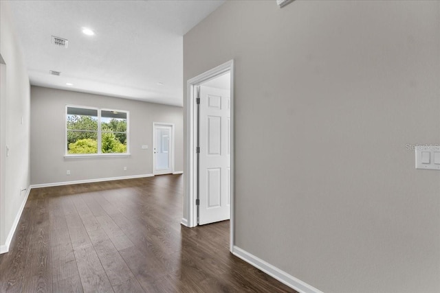 spare room with baseboards, visible vents, and dark wood-type flooring