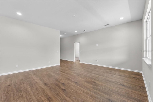 empty room with recessed lighting, visible vents, wood finished floors, and baseboards