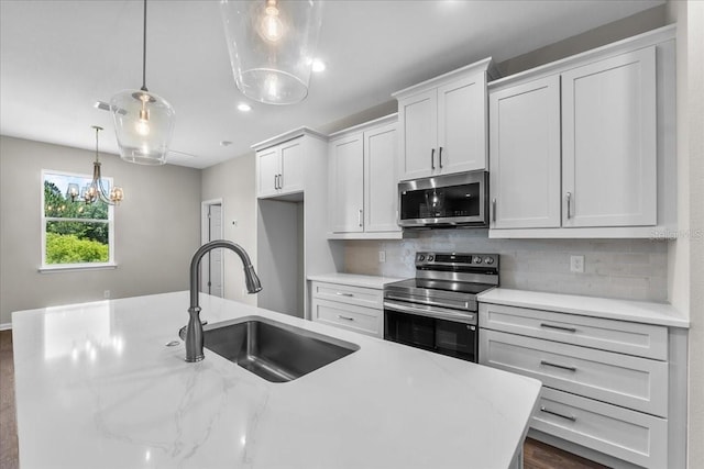 kitchen with a sink, stainless steel appliances, backsplash, pendant lighting, and white cabinets