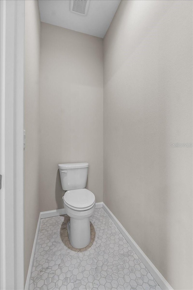 bathroom with baseboards, visible vents, tile patterned floors, and toilet