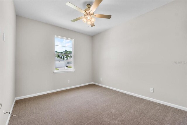 carpeted spare room with baseboards and a ceiling fan