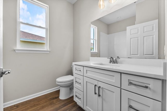 bathroom with baseboards, wood finished floors, toilet, and vanity
