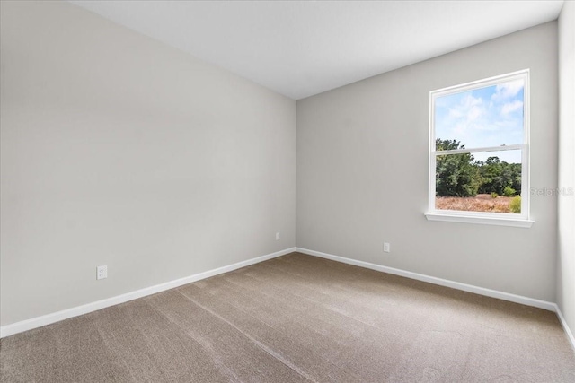 carpeted empty room featuring baseboards
