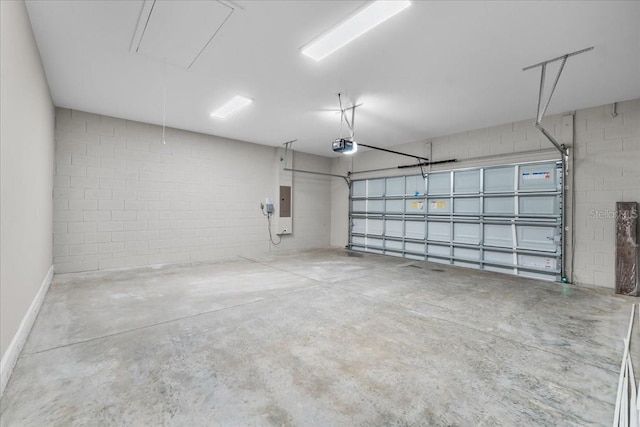 garage featuring baseboards, a garage door opener, concrete block wall, and electric panel