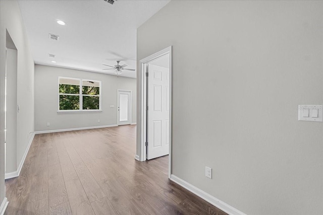 unfurnished room featuring wood finished floors, visible vents, a ceiling fan, and baseboards