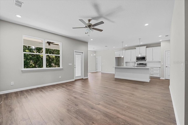 unfurnished living room featuring baseboards, visible vents, wood finished floors, and a ceiling fan