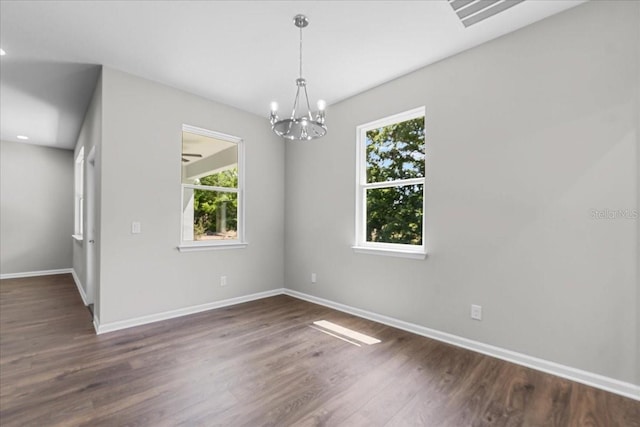 empty room with baseboards, wood finished floors, and a chandelier