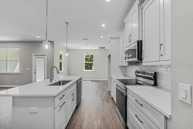 kitchen featuring recessed lighting, an island with sink, stainless steel appliances, dark wood-style flooring, and a sink