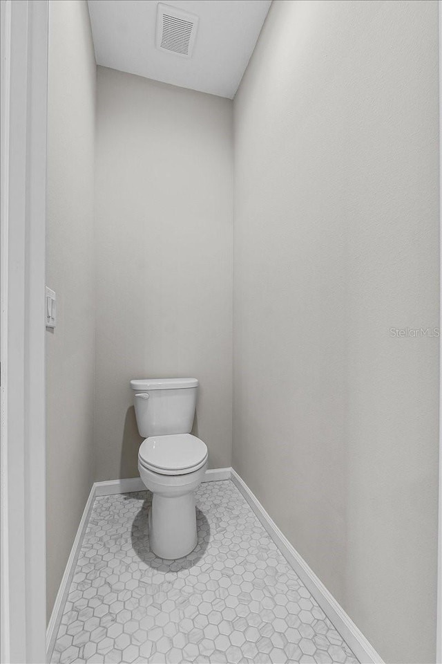 bathroom with baseboards, visible vents, tile patterned floors, and toilet