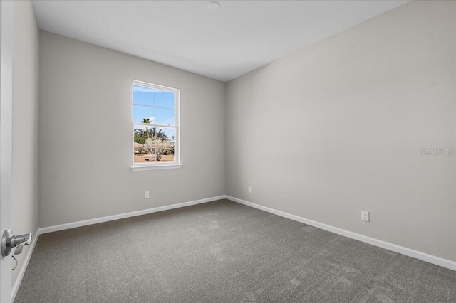 empty room featuring carpet and baseboards