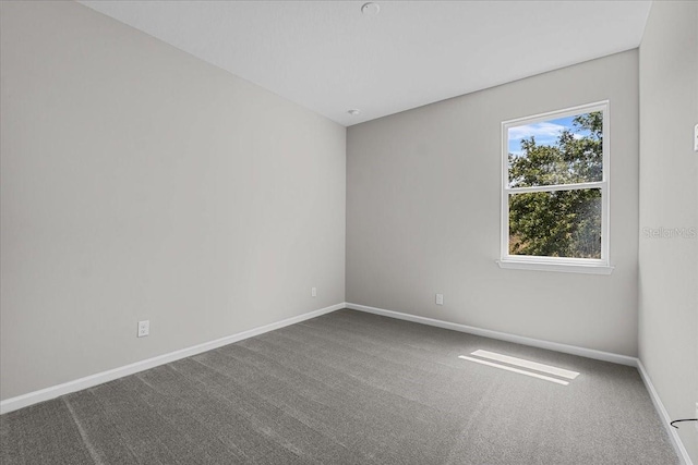 unfurnished room with carpet flooring and baseboards