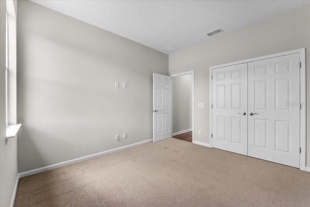 unfurnished bedroom featuring baseboards, visible vents, carpet floors, and a closet
