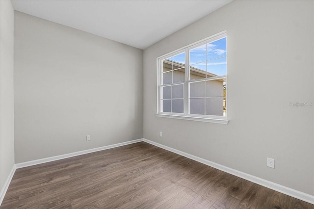 spare room with baseboards and wood finished floors
