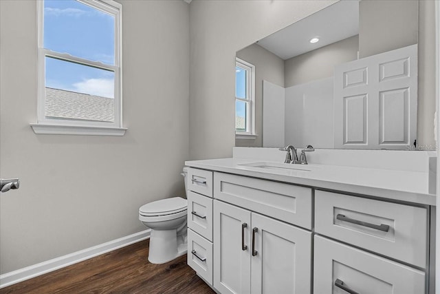 bathroom featuring toilet, vanity, wood finished floors, and baseboards