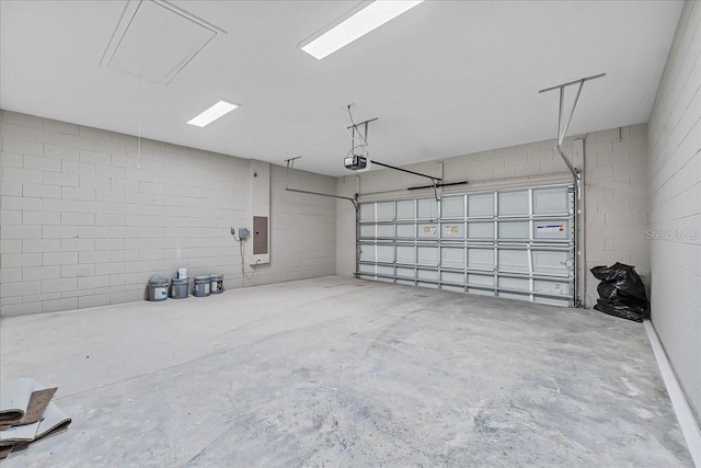 garage with a garage door opener, concrete block wall, and electric panel