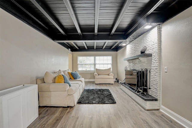 living room featuring beam ceiling, a brick fireplace, and hardwood / wood-style flooring