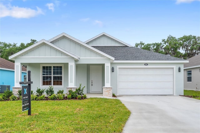 view of front of house featuring driveway, a shingled roof, a garage, and a front lawn