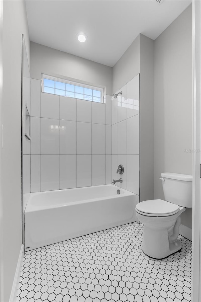 full bath featuring shower / washtub combination, toilet, and tile patterned flooring