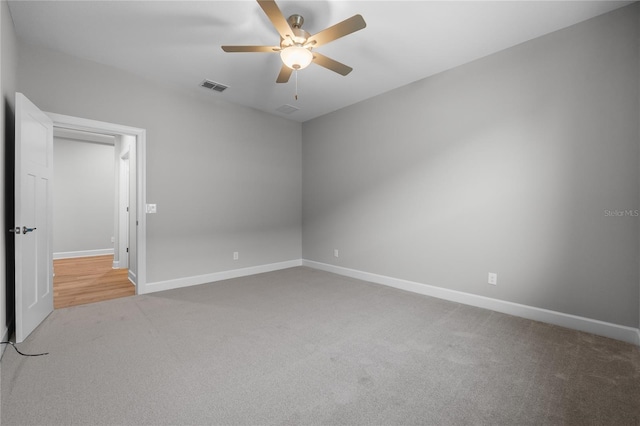 carpeted spare room with baseboards, visible vents, and a ceiling fan