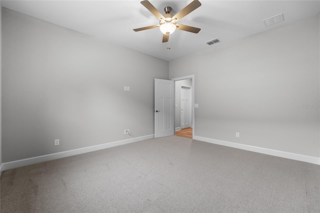 carpeted spare room with baseboards, ceiling fan, and visible vents