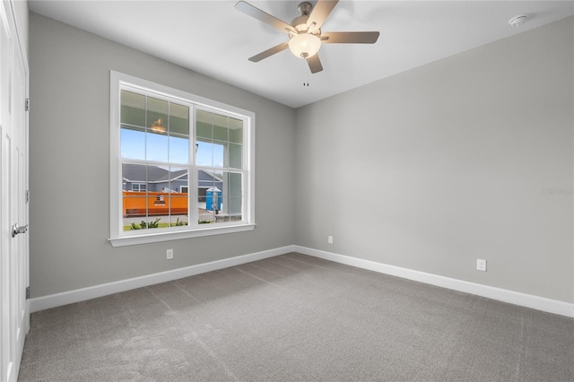 empty room with baseboards, ceiling fan, and carpet