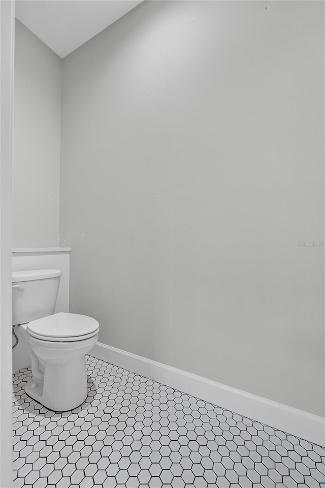 bathroom featuring baseboards, toilet, and tile patterned flooring