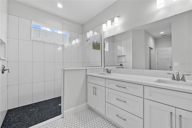 full bathroom featuring double vanity, visible vents, a sink, and walk in shower